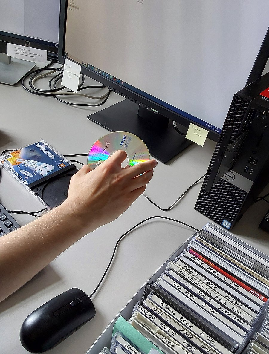 Hand, die eine CD in ein Laufwerk einführt